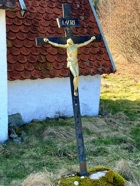Kreuz in Schieflage vor einem Backhusle