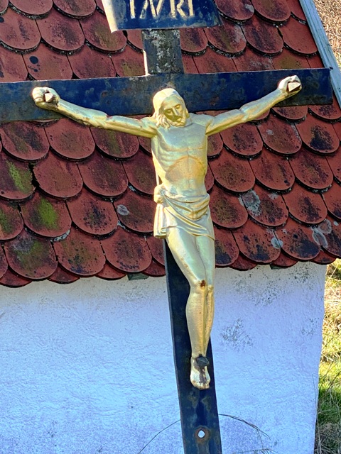 Kreuz in Schieflage vor einem Backhusle