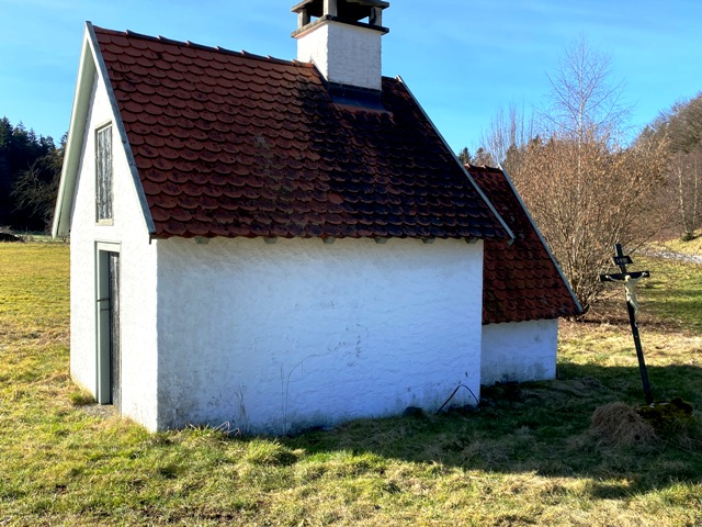 Kreuz in Schieflage vor einem Backhusle